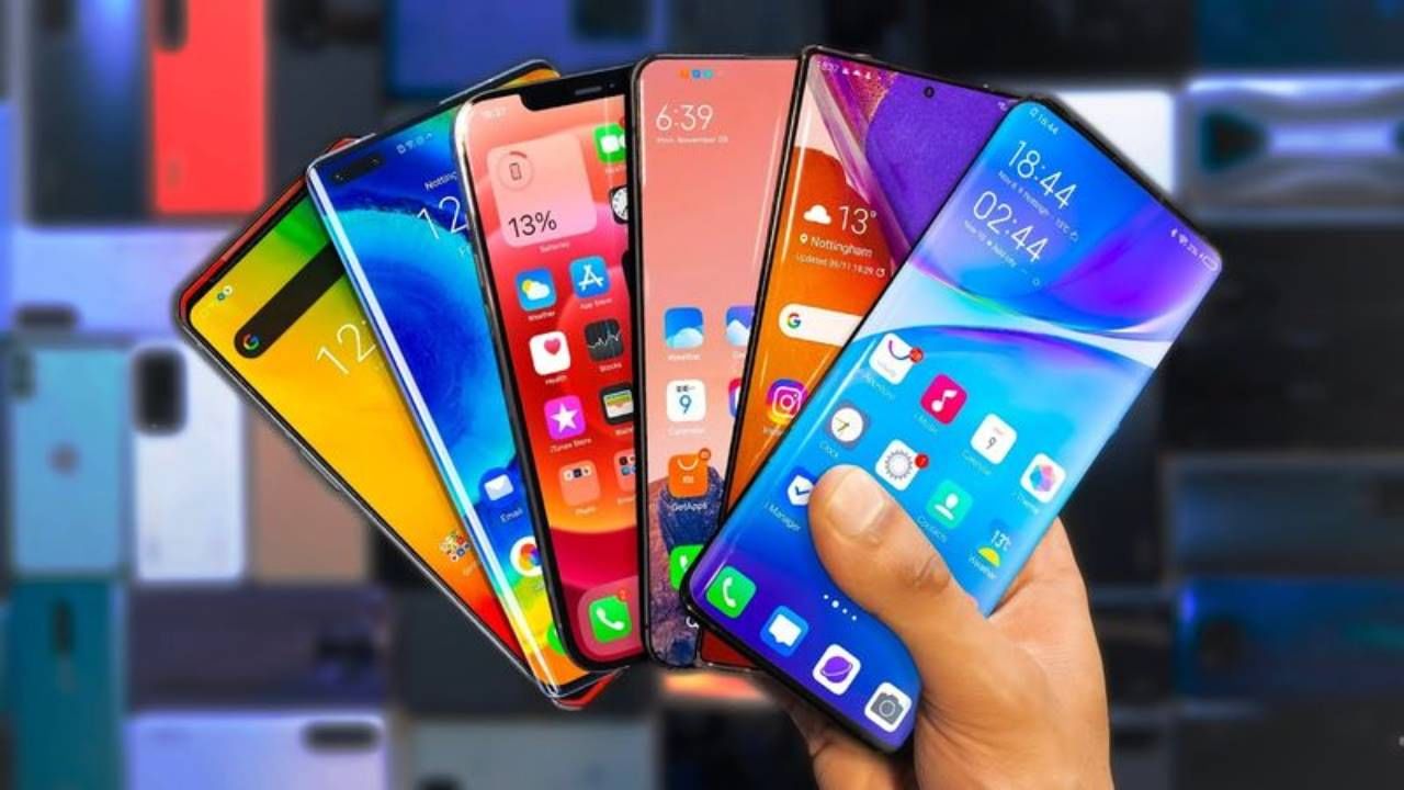  A hand holding a smartphone with several other smartphones in the background.