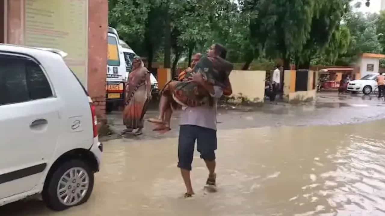 Man carries wife in arms: স্ত্রীকে কোলে নিয়ে জল পেরিয়ে হাসপাতালের পথে ব্যক্তি Man carries wife in arms: স্ত্রীকে কোলে নিয়ে জল পেরিয়ে হাসপাতালের পথে ব্যক্তি