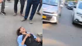 হাতে সিগারেট, পায়ের কাছে মদের বোতল! দিনে-দুপুরে মাঝ রাস্তায় শুয়ে যুবতী