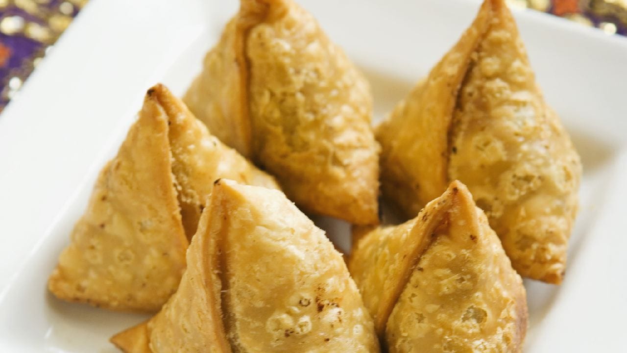 সিঙারাকে ইংরেজিতে সাধারণত ‘Samosa’ নামেই ডাকা হয়। অর্থাৎ এর জন্য আলাদা কোনও নির্দিষ্ট English translation নেই। তবে খাবারটি কী ধরনের, তা বোঝাতে ইংরেজিতে একে ‘triangular savoury pastry filled with spiced vegetables or meat’-এর মতো করে বর্ণনা করা যায়। এই বর্ণনাটি নাম নয়, খাবারটির গঠন ও উপকরণ বোঝানোর জন্য ব্যবহৃত হয়। Getty Images