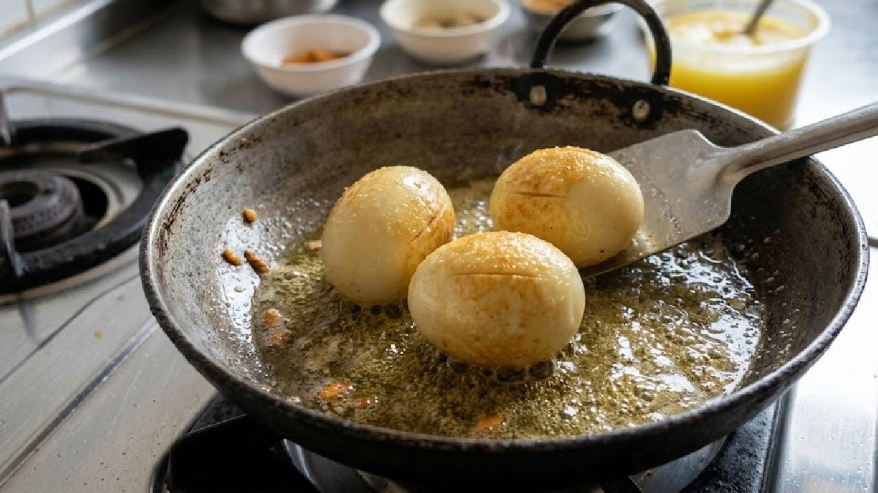 এই রান্নাটি শুরু করার জন্য প্রথমে প্যানে মাঝারি আঁচে দুই টেবিল চামচ ঘি ভালো করে গরম করে নিন। এরপর তিনটি সেদ্ধ ডিমের গায়ে হালকা করে চিরে নিয়ে সেই গরম ঘিয়ে লালচে করে ভেজে তুলে রাখুন। ডিমগুলো এভাবে আগে থেকে ভেজে রাখলে বাইরের অংশটি বেশ মুচমুচে হয় এবং পরে মশলার স্বাদ খুব সুন্দরভাবে ডিমের ভেতরে প্রবেশ করে। Ai Genareted